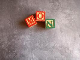 A photo of a wooden block with the words monday written on it, styled in isolation with space for text.