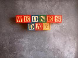 A photo of a wooden block with the words wednesday written on it, styled in isolation with space for text.