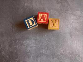 A photo of a wooden block with the words day written on it, styled in isolation with space for text.