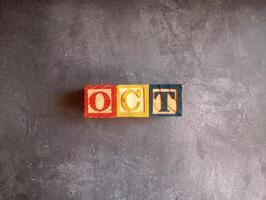 A photo of a wooden block with the words october written on it, styled in isolation with space for text.