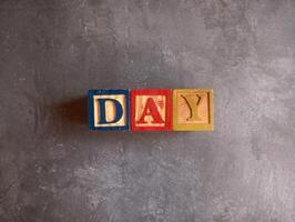 A photo of a wooden block with the words day written on it, styled in isolation with space for text.