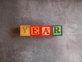 A photo of a wooden block with the words year written on it, styled in isolation with space for text.
