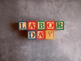 A photo of a wooden block with the words labor day written on it, styled in isolation with space for text.