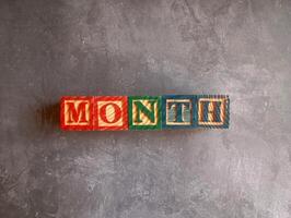 A photo of a wooden block with the words month written on it, styled in isolation with space for text.