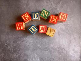 A photo of a wooden block with the words wednesday written on it, styled in isolation with space for text.