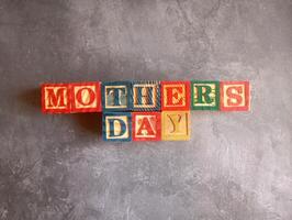 A photo of a wooden block with the words mothers day written on it, styled in isolation with space for text.
