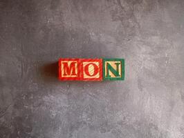 A photo of a wooden block with the words monday written on it, styled in isolation with space for text.