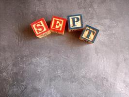 A photo of a wooden block with the words september written on it, styled in isolation with space for text.