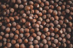 Hazelnuts in a wooden bowl on rustic background, Hazelnut background with green leaf photo