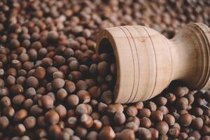 Hazelnuts in a wooden bowl on rustic background, Hazelnut background with green leaf photo