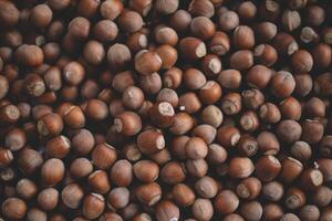 Hazelnuts in a wooden bowl on rustic background, Hazelnut background with green leaf photo