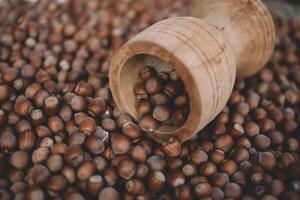 Hazelnuts in a wooden bowl on rustic background, Hazelnut background with green leaf photo