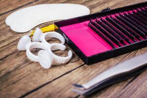 Eyelash Extension tools on wooden background. Accessories for eyelash extensions. Artificial lashes. Close up. photo