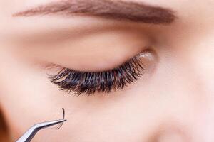 Eyelash Extension Procedure. Woman Eye with Long Eyelashes. Lashes, close up, macro, selective focus. photo