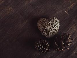 Yarn heart with dried pine cones on old wood, vintage, Valentine's Day concept. photo