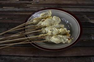 A plate of sempol, a type of fried food made from tapioca flour dough, shaped into ovals and skewered, with a chewy texture, eaten with spicy red sauce and soy sauce or peanut sauce can be added. photo