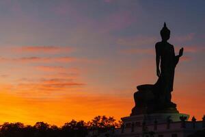 un majestuoso silueta de Buda estatua en contra vibrante puesta de sol cielo, exhibiendo sereno belleza de espiritualidad y naturaleza. calentar colores evocar sentido de paz y reflexión foto