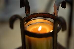 A candle is lit in a metal holder photo