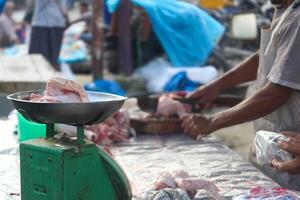 Raw chicken pieces are weighed for sale. Indonesian traditional market atmosphere photo