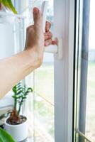 The hand holds the handle of a plastic double-glazed window, closing and opening the window with a rotary mechanism, the position of the handle for ventilation, micro-ventilation photo