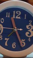 Close up of unusual alarm clock of blue color with white frame. Concept. Blue alarm clock with white numbers and metal hands standing on the table in the room. video