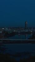 Top view of landscape of evening city with lanterns and river. Stock footage. Beautiful panorama of city with reflection of sunset light on glass skyscrapers. Dark twilight over glowing metropolis video