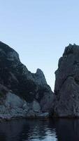 Top view of wild cliffs with blue sea on sky background. Shot. Rocky coast with calm water of blue sea reaching horizon on background of sky video