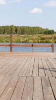 madera muelle encima el río y el bosque con prado en el opuesto costa. valores imágenes. verano rural paisaje con verde arboles y césped, río y muelle. video