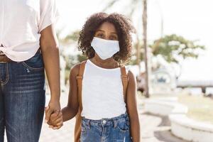 Portrait of an African American Girl with Backpack Wearing Mask. Back to School and New Normal Concept photo