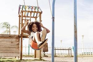 happy and smiling african american girl playing on swing. fun and recreation concept. photo