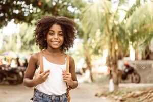 portrait of a smiling afro american girl holding with hands a backpack. back to school concept. photo