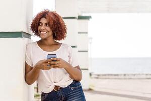 happy afro woman using a mobile phone with copy space. communication and technology concept. photo