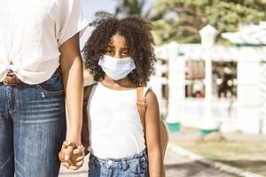 Portrait of an African American Girl with Backpack Wearing Mask. Back to School and New Normal Concept photo