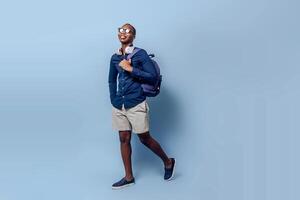tourist black african man with backpack, headphones and sunglasses traveling with copy space on studio. photo