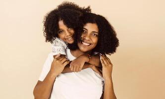 afro american mother and daughter smiling happy hugging over isolated background. photo