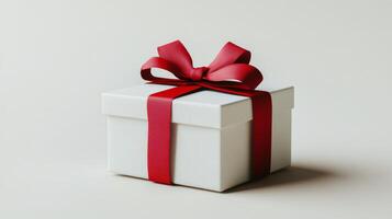 A beautifully wrapped white gift box with a red ribbon sits on a light background photo