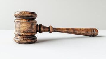 A classic wooden gavel resting on a clean white surface illuminated by soft light photo