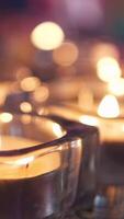 ardiente velas en mesa en el oscuridad. concepto. cerca arriba de pequeño velas en vaso candelabros en pie en el mesa en oscuro habitación creando romántico atmósfera para fecha. video
