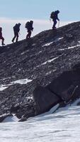 Climbers climb the mountain with snow field. Four climbers ascend the hill video