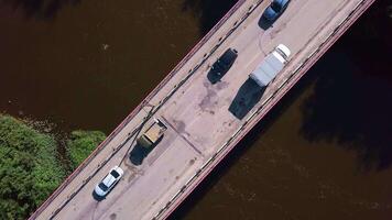 A view over a place for cars to move over a dirty river. Clip.A bird's-eye view of moving trucks over the river and forests around. video