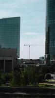 View of the metropolis from a height. Stock footage. Sunny landscape on tall buildings made of glass and parks around the river on the background of blue sky. video