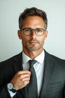 Professional man adjusting tie while wearing glasses in a formal setting photo