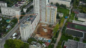 Top view of construction site of house on background of city with river. Stock footage. Construction of residential building on background of horizon with river. Construction of buildings in city with video