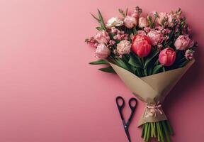 Beautiful bouquet of pink and white flowers on a pink background with scissors nearby photo
