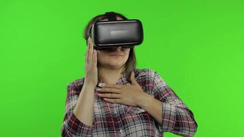 Girl using VR app helmet to play simulation scary game. Woman watching virtual reality 3D video