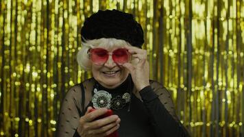 Stylish senior old woman typing message on social network, using app, online shopping. Slow motion video