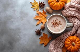 Cozy fall coffee arrangement with pumpkin, knit sweater, and autumn leaves on a gray background photo