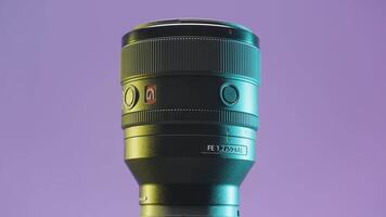 Italy - Rome, june 23, 2022. Close up of a modern camera lens rotating slowly on a lilac wall background. Action. Professional equipment for photographers. video