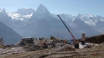 Construction site on background of mountain peaks. Creative. Construction with heavy transport in mountains. Construction site high in mountains on background of snowy peaks video