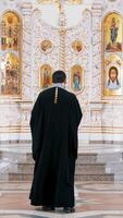 The Iconostasis inside an orthodox church. . Rear view of a priest standing in front of the icons with the faces of the saints, concept of religion, interior details inside a church. video